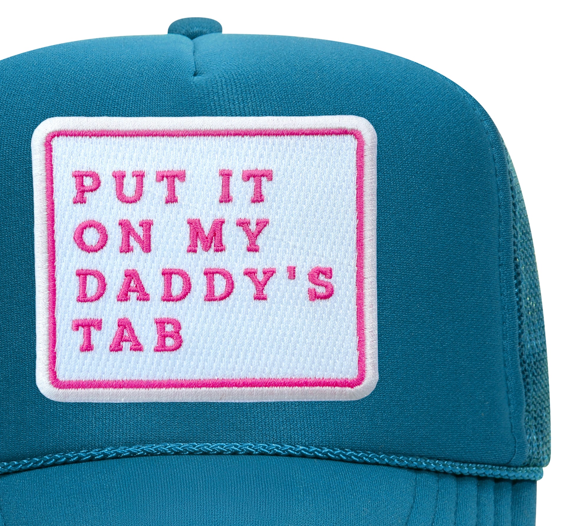 Close-up of the Put It On My Daddy's Tab embroidered patch on a turquoise trucker hat