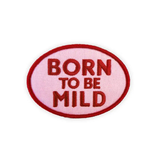 An oval embroidered patch with a light pink background and dark red border and text reading 'BORN TO BE MILD' on a plain white background.