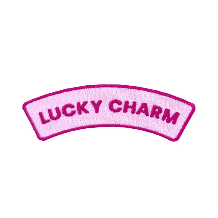 Lucky Charm embroidered iron-on patch, arched banner in pale pink with a hot pink border, on a white background