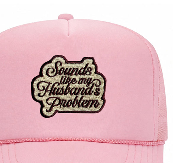Close-up of the Sounds Like My Husband's Problem embroidered patch on a soft pink trucker hat